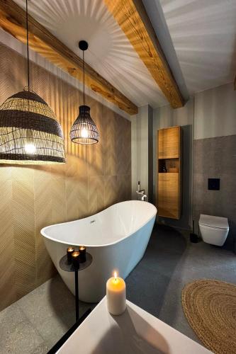 a bathroom with a bath tub and a candle at Siedlisko 3 Stodoły Bałtów - SPA w naturze in Bałtów