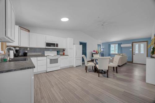 Una cocina con gabinetes blancos y una mesa y sillas. en Tucked Away Walk to Beach Pet Friendly Relax, en Rothesay