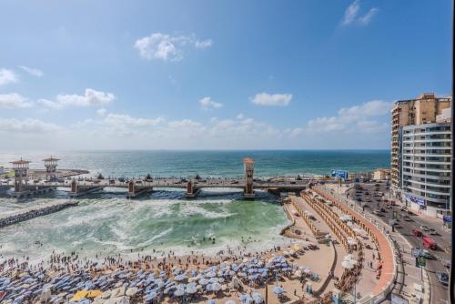 a beach with people and umbrellas and the ocean at Nabeel Homes - Panoramic Seaview Condo in Stanley in Alexandria