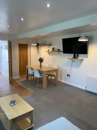 a living room with a table and a tv on the wall at Wyndham studio in Uphill