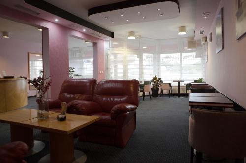 a waiting room with a leather couch and a table at Hotel Millennium in Osijek