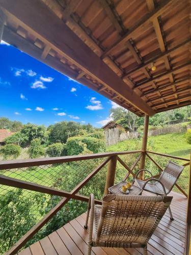 a balcony with two chairs and a view of the forest at Chalé Som da Sete Quedas Hidromassagem, Lareira e Vista para as Montanhas in Gonçalves