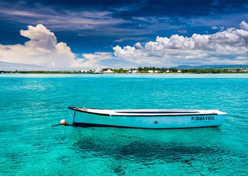 a boat sitting in the water in the ocean at Tamam beach shack in Mahébourg
