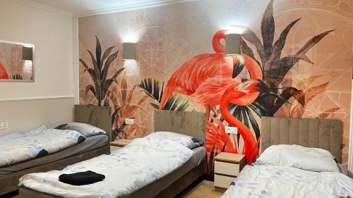 two beds in a room with a mural of flamingos at Pokoje Hotelowe "Lila" Siedlce in Siedlce