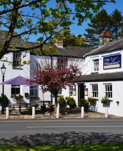 ein weißes Gebäude mit einem violetten Sonnenschirm davor in der Unterkunft Pheasant Inn in Kirkby Lonsdale