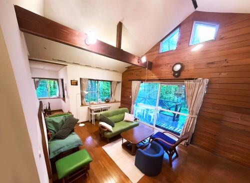 a living room with green furniture and a large window at 森の中で仲間や家族とゆっくり過ごせる温泉付コテージ 会員制別荘地で広大なプライベート空間 ペット可 那須高原りんどうハウス in Nasu