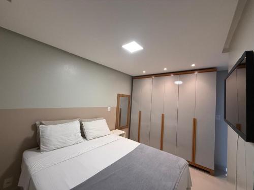 a bedroom with a white bed and a tv at COP30 - Apartamento completo para alugar in Ananindeua