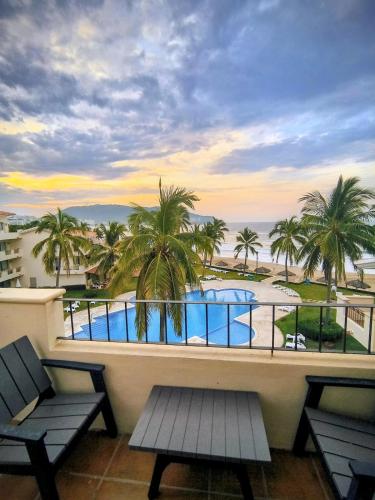 a balcony with a view of a pool and palm trees at Frente al Mar totalmente remodelado para 6 personas in Ixtapa
