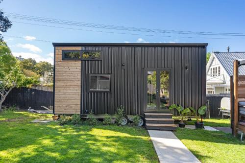 a small black tiny house in a yard at Tiny Home Escape w Sauna and Plunge in Whangarei