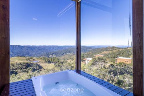 a bath tub in a room with a large window at Linda cabana com jacuzzi e vista incrível VST004 in São Paulo dos Pinhais