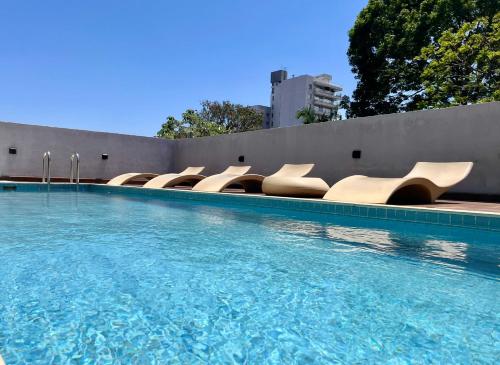 a swimming pool with a row of white chairs at Charlotte Belgrano Posadas in Posadas