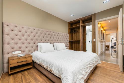 a bedroom with a large white bed with a large headboard at Appartement avec salle de cinema in Agadir