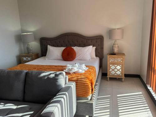 a bed in a room with a couch and a bed with orange blanket at Rooftop Pool Condo in Kingston in Kingston