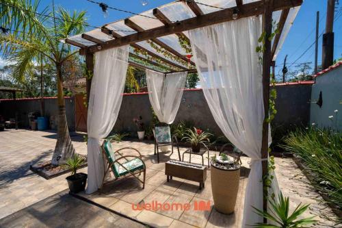 een houten pergola met 2 stoelen en een tafel bij Sitio com piscina e lazer completo em Mongagua in Agenor de Campos