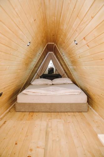 a bed in a wooden room with a wooden floor at Vikendica Buzadzija M&N in Piskavica