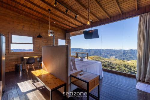 a room with a bed and a table and a large window at Linda cabana com jacuzzi e vista incrível VST004 in São Paulo dos Pinhais