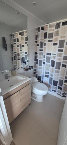 a bathroom with a toilet and a sink and a mirror at Condominio Parque Mar El Tabo in El Tabo