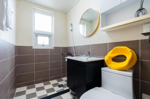 a bathroom with a toilet with a yellow seat at Domostay in Seogwipo