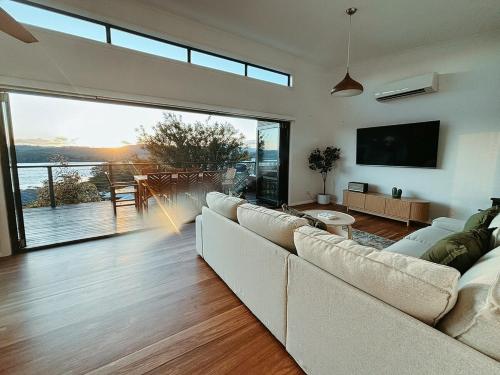 a living room with a white couch and a large window at Snapper Hideaway - Pet Friendly in Merimbula