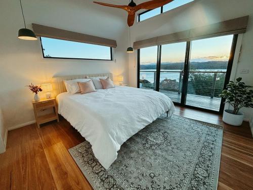 a bedroom with a white bed with a large window at Snapper Hideaway - Pet Friendly in Merimbula