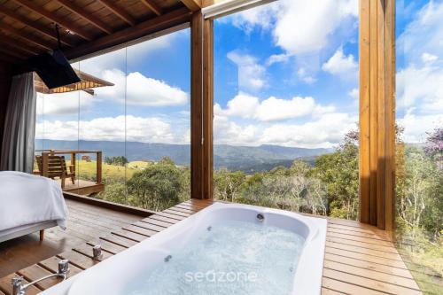 a bath tub in a room with a large window at Cabana com Vista Serra em Anitápolis VST032 in São Paulo dos Pinhais