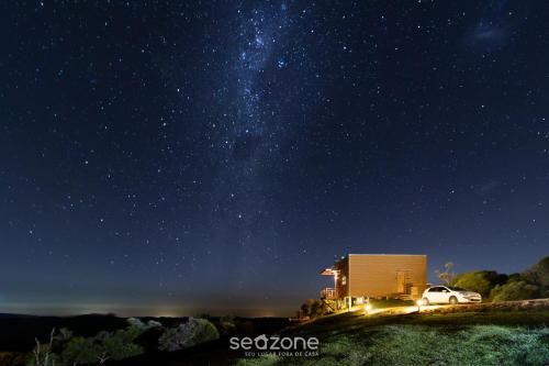 a starry night with a building and a car parked next to it at Cabana com Vista Serra em Anitápolis VST032 in São Paulo dos Pinhais