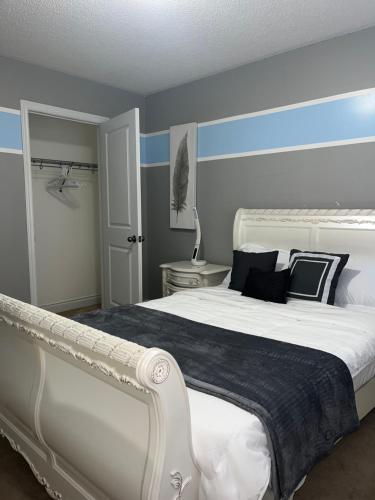 a bedroom with a white bed with blue stripes at 3300 SqFt - Modern and Comfort - 3 BDRM Getaway - Relax - Unwind - Explore - Near Toronto Pearson Airport & Toronto Downtown in Brampton