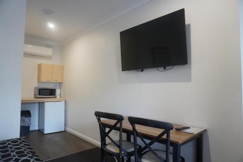 a room with a table and a television on a wall at Wagga Gardens Motel in Wagga Wagga