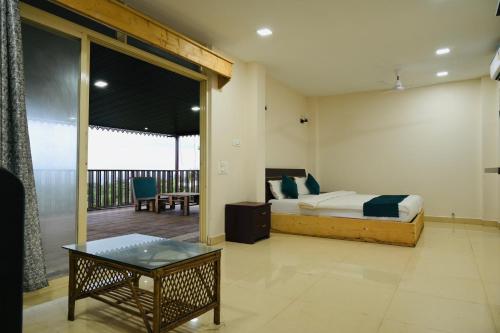 een slaapkamer met een bed en een balkon met een tafel bij Hotel Anandam Elegance in Morjim