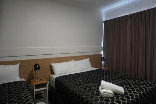 a hotel room with a bed with two white towels on it at Wagga Gardens Motel in Wagga Wagga