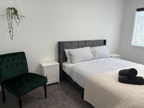 a bedroom with two beds and a green chair at Space, Style and Serenity in Lower Hutt