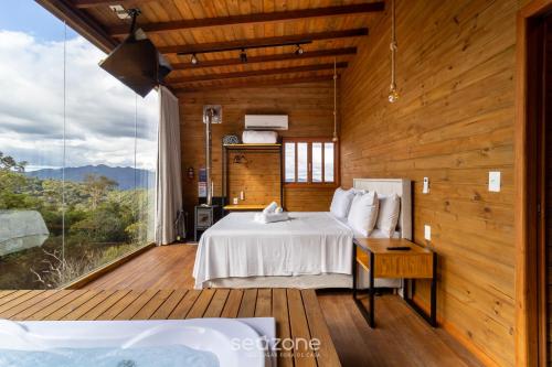 une chambre avec un lit et une grande fenêtre dans l'établissement Cabana c/ vista e jacuzzi Serra Catarinense VST025, à São Paulo dos Pinhais