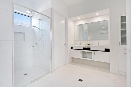 a white bathroom with a shower and a sink at Ocean Breeze on Malibu in Kingscliff