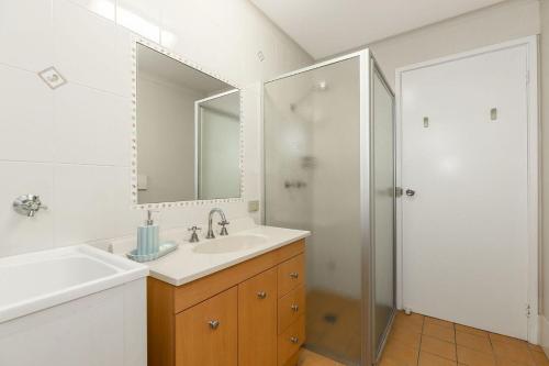une salle de bain blanche avec lavabo et douche dans l'établissement Lakeside Apartments 4, à Merimbula