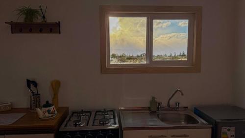 a kitchen with a window above a sink and a stove at Eco-Bungallow in Puerto Natales