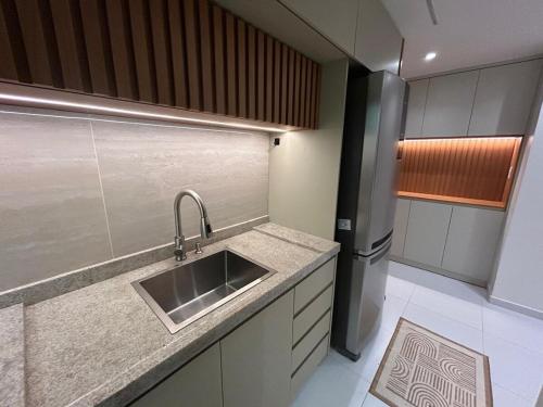 una cocina con fregadero y refrigerador en Cobertura pé na areia, 3 suítes e área externa, en Ilhéus