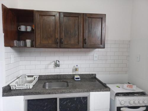 a kitchen with a sink and wooden cabinets at Apart Lua Crescente - de casal até 5 pessoas na Pituba caminho das praias in Itacaré