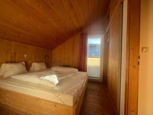 a bed in a wooden room with a window at Spatzennest in Hohentauern