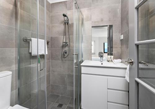 un baño con ducha y lavabo en Morning Glow - Wake up to breathtaking views and golden sunrises at this serene coastal retreat., en Bombo