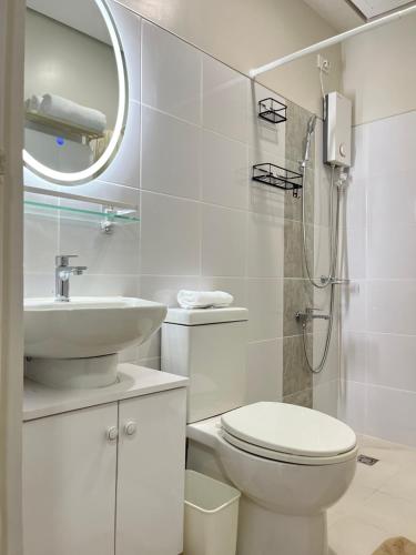 a white bathroom with a toilet and a sink at Aspen Suites Condo in Davao City