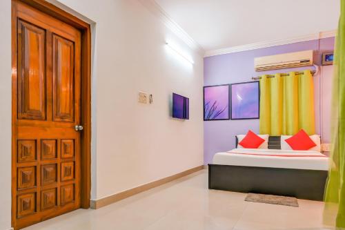 a bedroom with a bed with red pillows and a door at Hotel O DREAM INN in Khandagiri