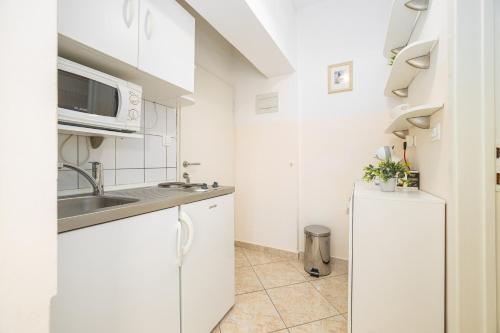 a white kitchen with a sink and a refrigerator at Apartments by the sea Duce, Omis - 946 in Duće