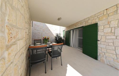 Amazing Apartment In Privlaka في Glavan: فناء مع طاولة وكراسي وجدار حجري