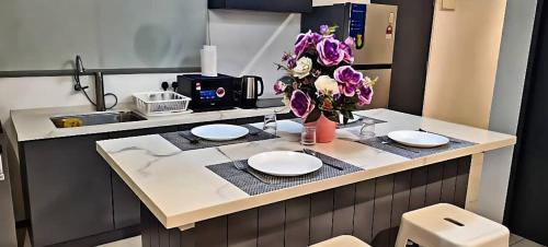 d'une cuisine avec une table avec des assiettes et des fleurs. dans l'établissement Urban Suites Georgetown Penang - Affordable & Cozy Stay with High Floor-Sea & Penang Bridge View, à George Town