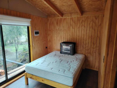a bed in a wooden room with a window at Cabañas Del Monte 2 in Melipeuco
