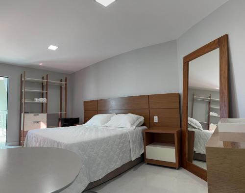 Un dormitorio con una cama y un espejo grande. en Hotel Conceito, en Tareco