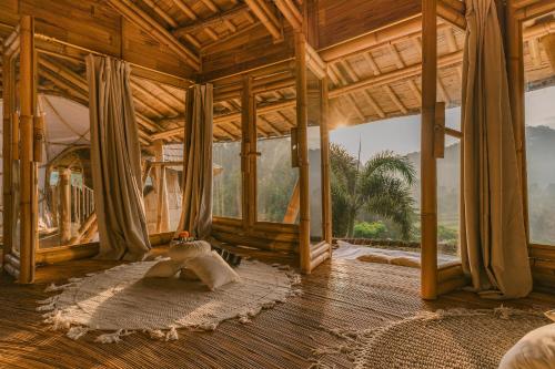 Una mujer acostada sobre una alfombra en una habitación con ventanas. en Luxury Bamboo Villa, en Selat