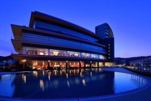 a building with a pool in front of it at night at Biwako Hotel in Otsu