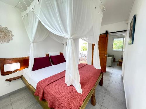 a bedroom with a bed with a canopy at Tibo bas de villa NEUF accès mer in Deshaies
