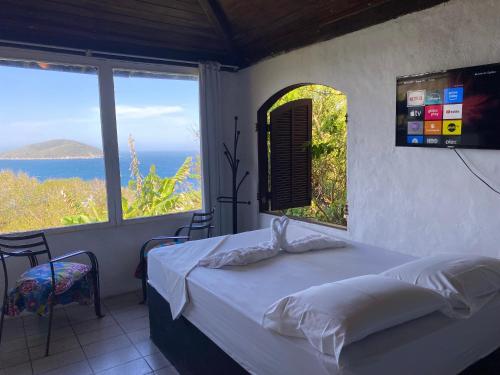 a bedroom with a bed with a view of the ocean at Bangalô Pontal do Atalaia com piscina para casal ou família in Arraial do Cabo